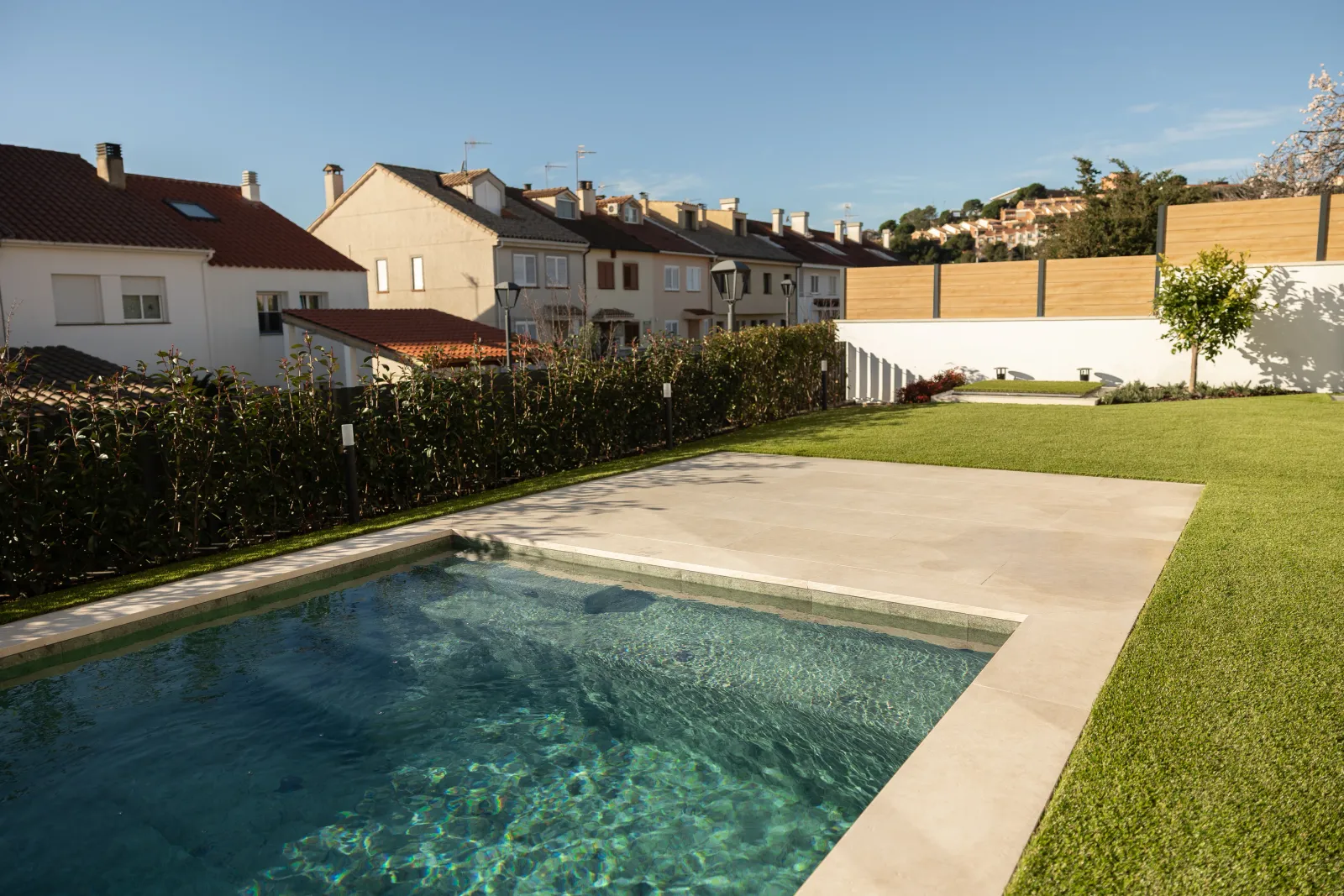 Exterior residencial con piscina, césped y cerramiento de madera tecnológica